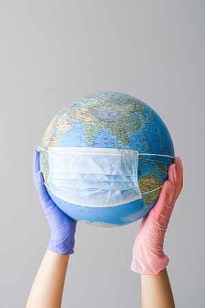 hands with latex gloves holding a globe with a face mask