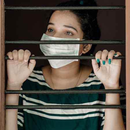 woman in green and white stripe shirt covering her face with white mask