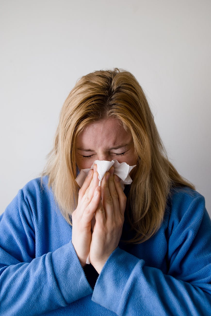 sick woman wiping her nose with tissue