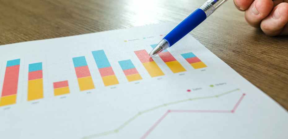 person holding pen pointing at graph