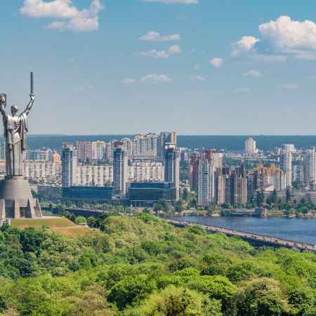 motherland monument among green trees on embankment in kiev
